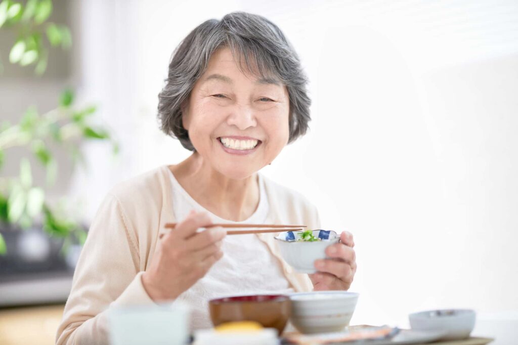 インプラント治療後も適切なメンテナンスをして快適に食事をする女性
