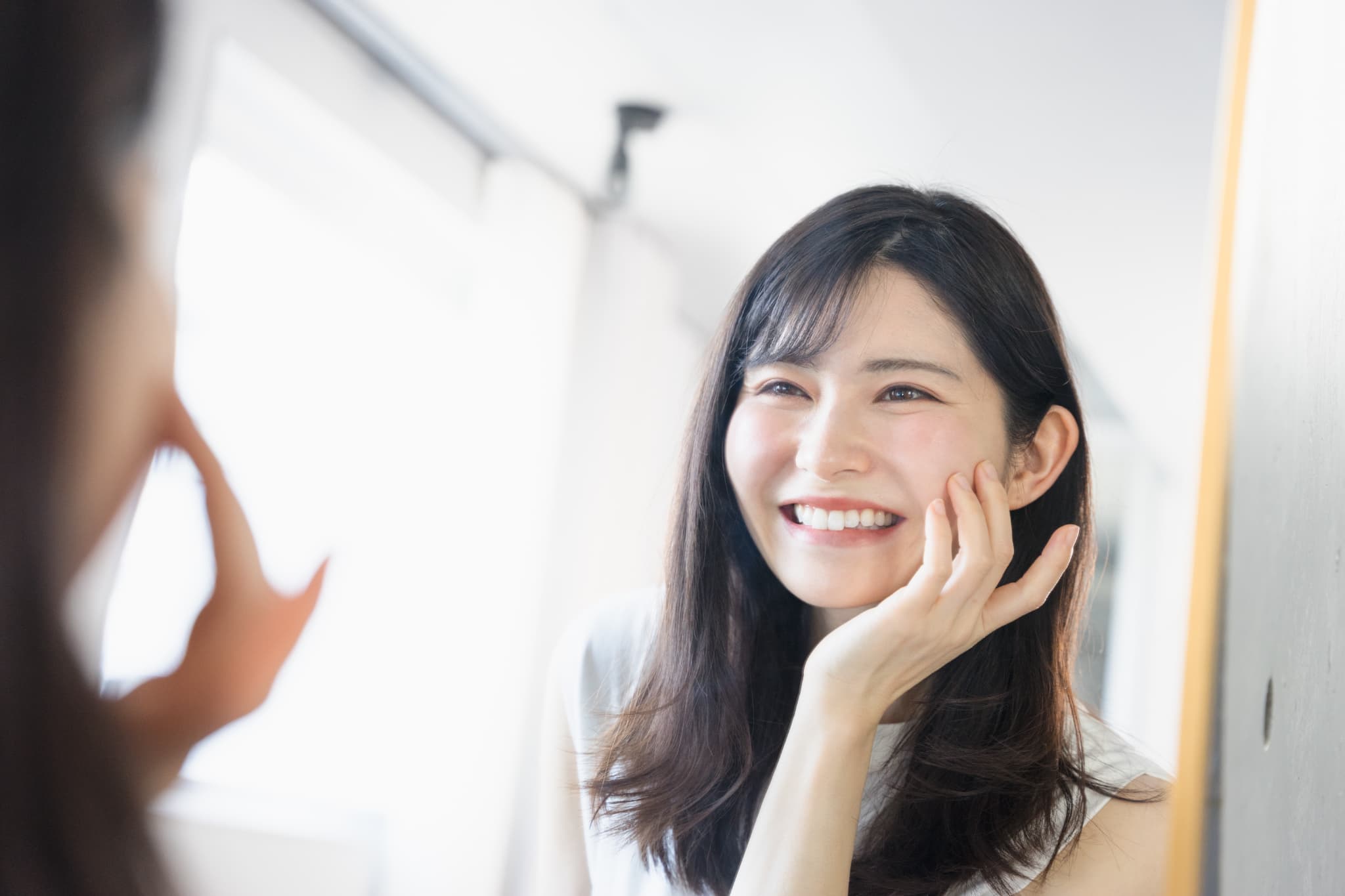 鏡でインプラント手術をした歯を確認する女性