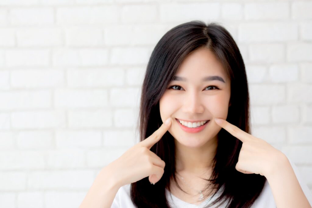 歯周病を治療した歯茎を指さし笑顔を見せる女性