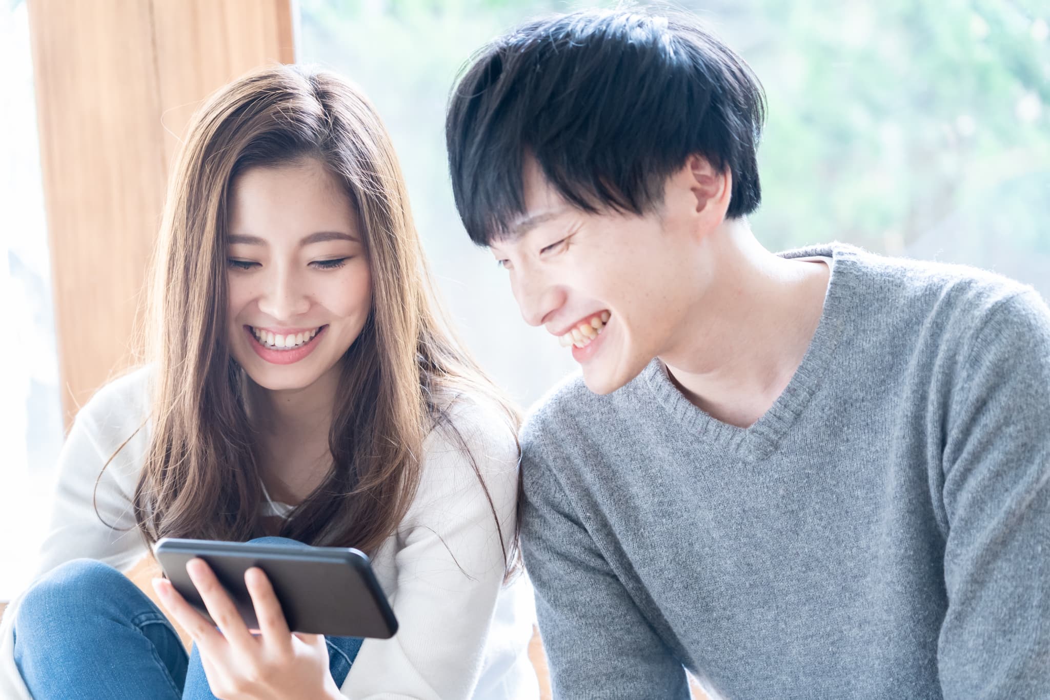 2人でスマホを見ている笑顔のカップル