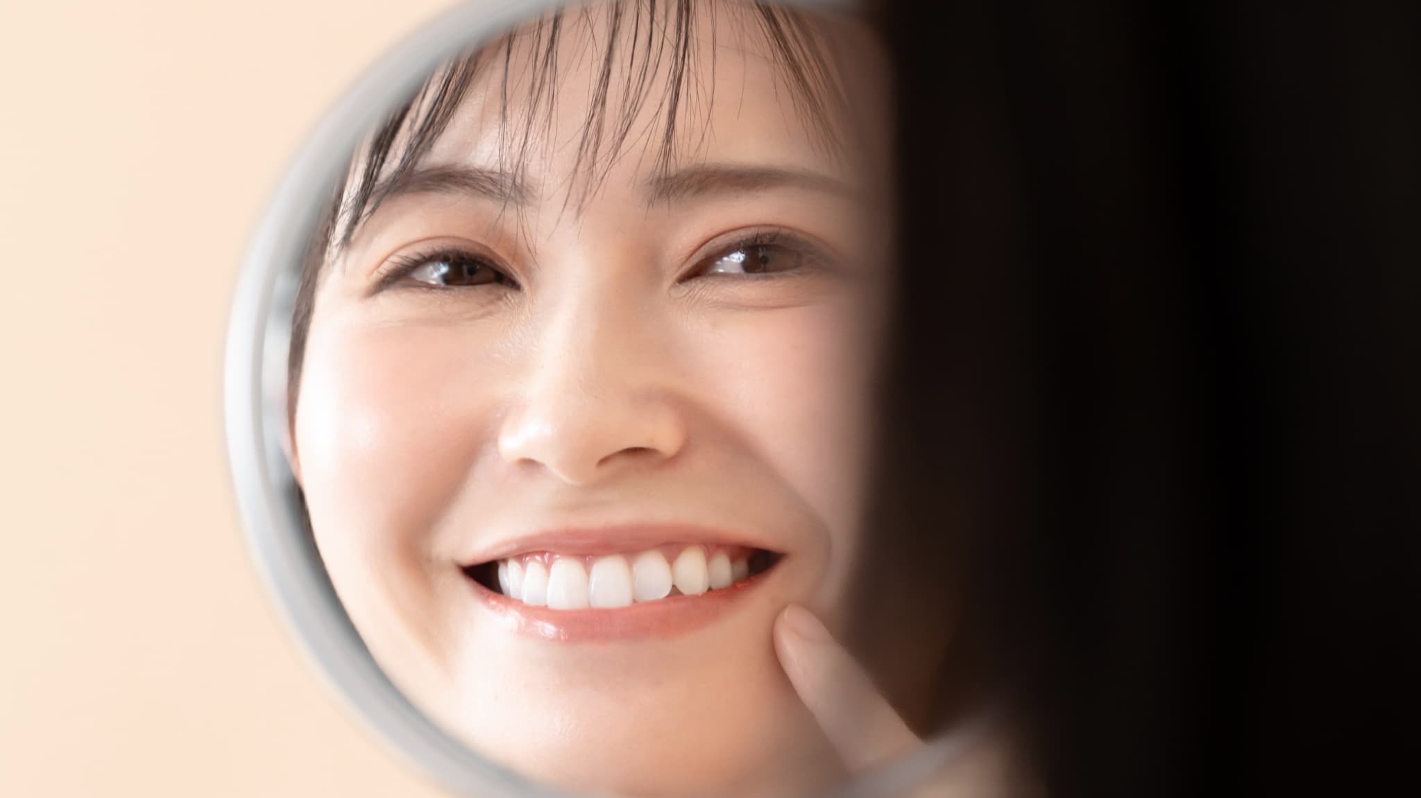 ホワイトニングで白くなった歯を鏡で見る女性