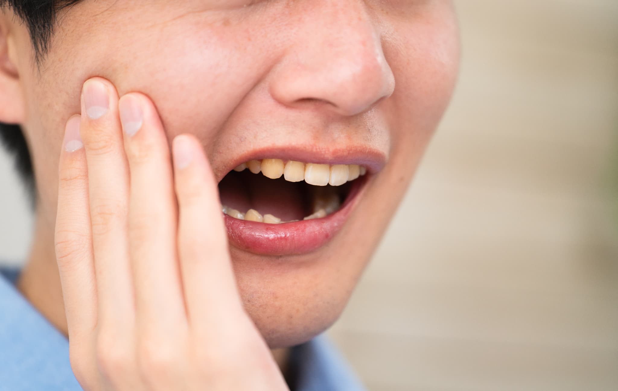 親知らずが痛くて頬を抑える男性