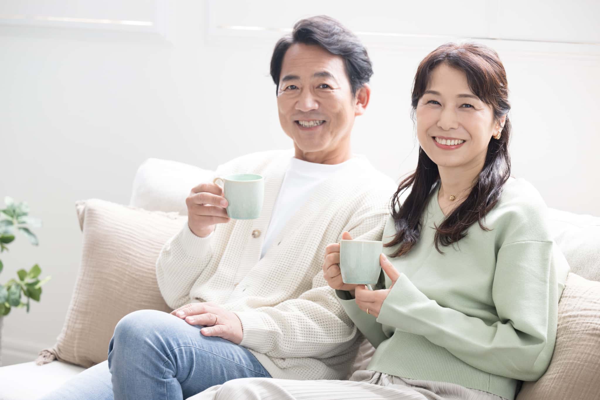 妻とソファで飲み物を飲んで寛いでいる歯周病を治療した男性