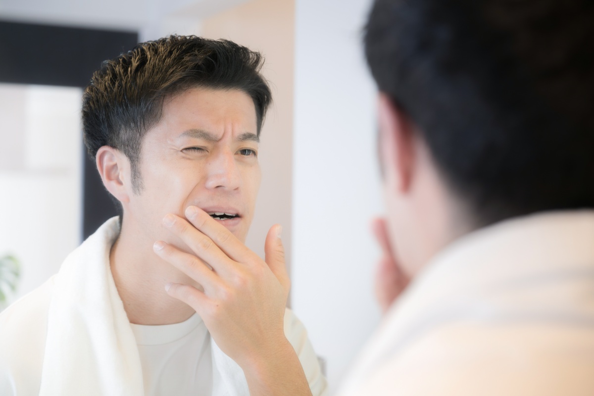 鏡で痛む歯茎を確認する男性